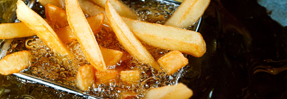 Einige Pommes blubbern sich in der Fritteuse knusprig.